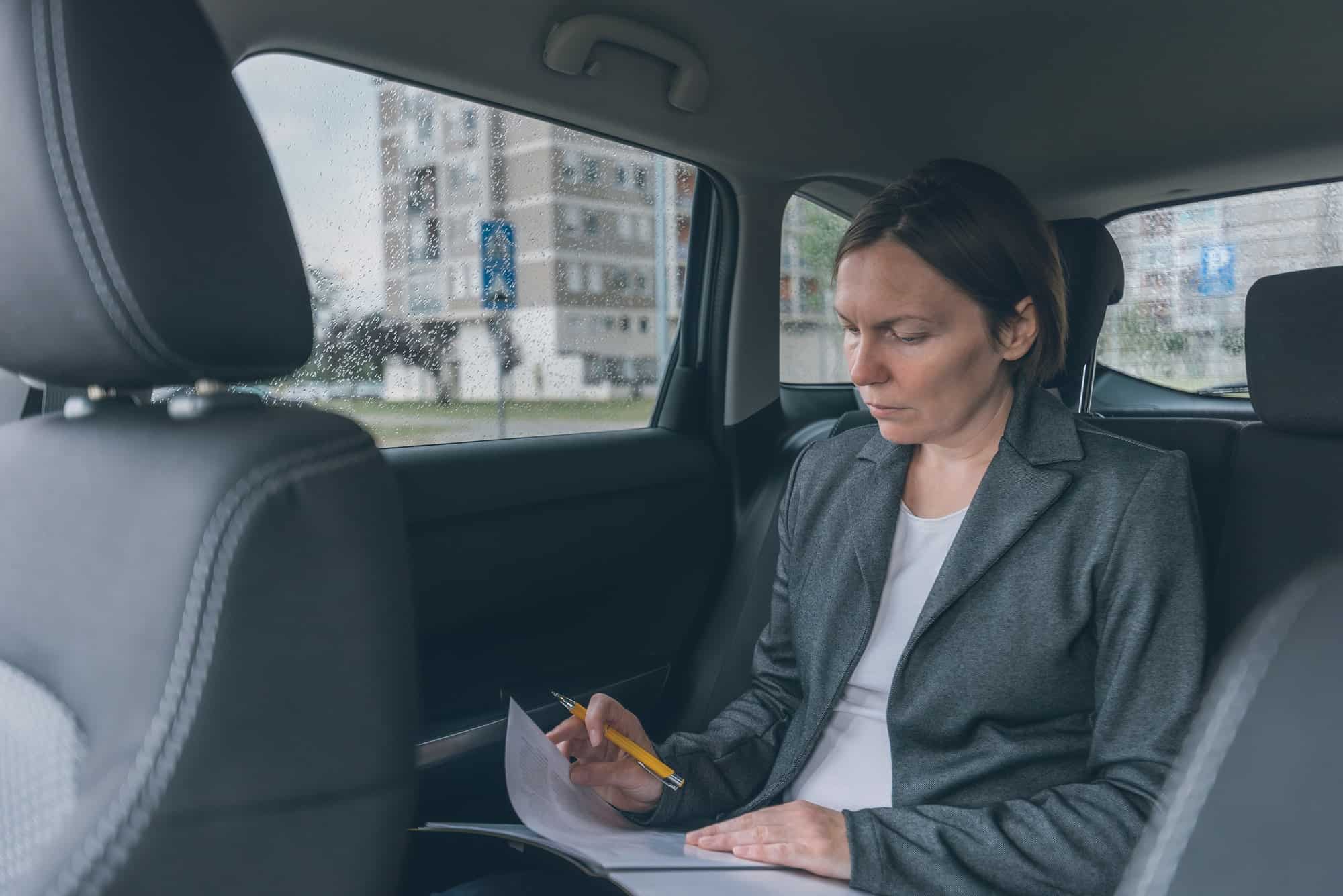 businesswoman-doing-business-paperwork-on-car-back-seat.jpg